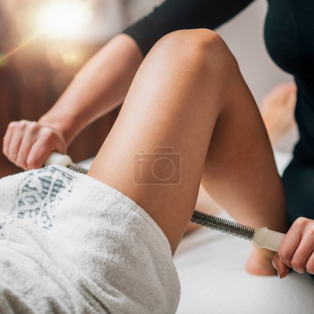 Photo for Metal Roling Pin Anti-Cellulite Treatment. A massage therapist treats cellulite affected area with a metal rolling pin - Royalty Free Image