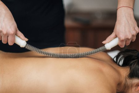 Photo for Back scraping massage with metal rolling pin - Royalty Free Image