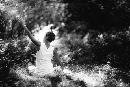 Téléchargez les photos : Connecting with Nature, Mindfulness Meditation. Une femme consciente qui médite, entourée par une belle nature - en image libre de droit