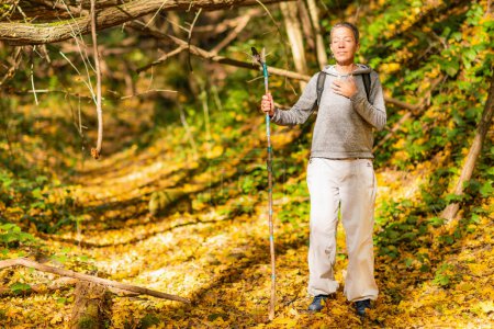 Foto de Mindfulness caminando. Mujer de mediana edad consciente caminando por el bosque de otoño. - Imagen libre de derechos