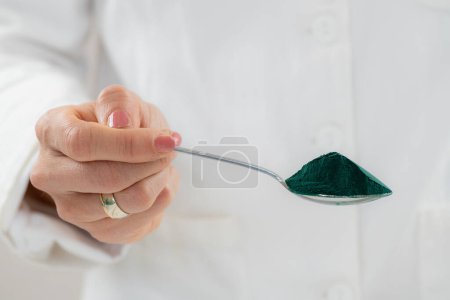 Photo for Spirulina, also known as blue-green algae in a close-up photo. Spoon full with spirulina, a nutrient-rich goodness and vibrant green color - Royalty Free Image