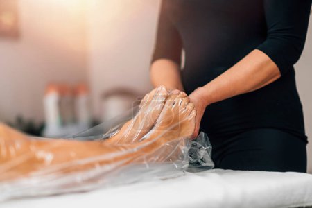 Téléchargez les photos : Anti-cellulite traitement minceur sous vide avec un sac en nylon pour les jambes. Femme cliente allongée sur une table de massage dans un centre de bien-être beauté. - en image libre de droit