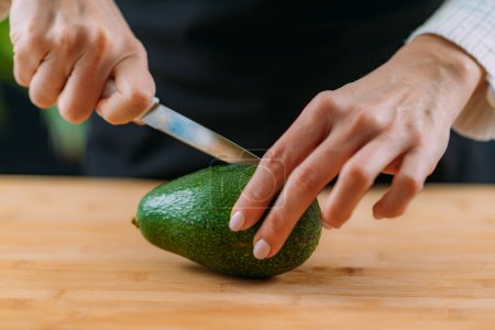 Photo for Woman Cutting fresh, organic avocado, superfood rich in monosaturated fat, vitamins, minerals, fibers and phytonutrients - Royalty Free Image