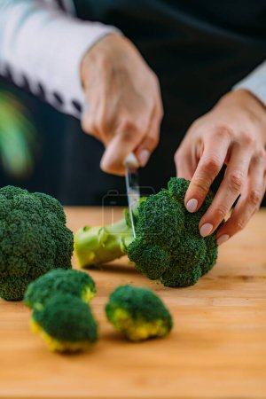 Foto de Mujer Cortar brócoli orgánico fresco, superalimento rico en vitamina K, vitamina C, ácido fólico, potasio, fitonutrientes y fibras - Imagen libre de derechos
