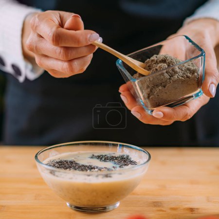 Foto de Mujer haciendo harina de avena con avena y leche de soja, Superfood rico en proteínas, fibras dietéticas, minerales y fitonutrientes - Imagen libre de derechos