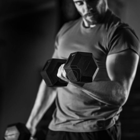 Photo for Black and white photo showcasing a handsome young man passionately engaged in a rigorous dumbbell workout, sculpting his physique - Royalty Free Image