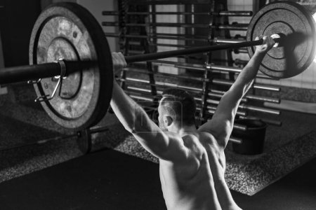 Photo for Dedicated male athlete excelling in cross training by lifting heavy barbells, symbolizing strength and determination, black and white photo - Royalty Free Image