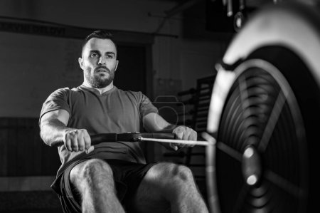 Photo for Young man excelling in a rowing machine exercise during cross training, dynamic black and white photo - Royalty Free Image