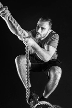 Téléchargez les photos : Détermination d'un passionné de cross training conquérant un exercice d'escalade en corde - en image libre de droit