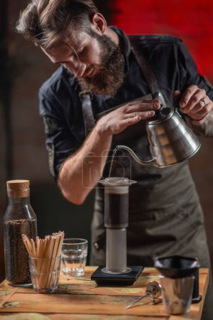 Téléchargez les photos : Talentueux barista utilisant la cafetière Aeropress pour créer une tasse de café riche et savoureuse - en image libre de droit