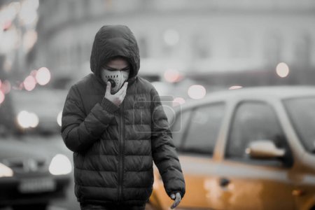 Foto de Contaminación del aire en una ciudad, niño con máscara respiratoria, tráfico pesado en segundo plano; concepto de emisión de carbono - Imagen libre de derechos