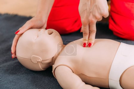Téléchargez les photos : Apprendre la RCR infantile dans une formation de premiers soins cours de réanimation cardiopulmonaire à l'aide d'un mannequin de bébé. - en image libre de droit