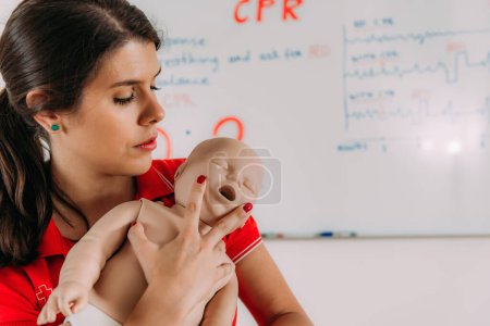 Téléchargez les photos : Apprendre la RCR infantile dans une formation de premiers soins cours de réanimation cardiopulmonaire à l'aide d'un mannequin de bébé. - en image libre de droit