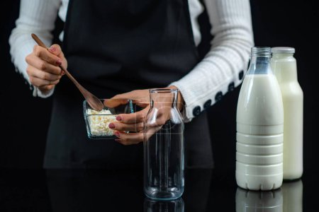 Téléchargez les photos : Femme Faire du kéfir, une boisson au lait fermenté, à la maison - en image libre de droit