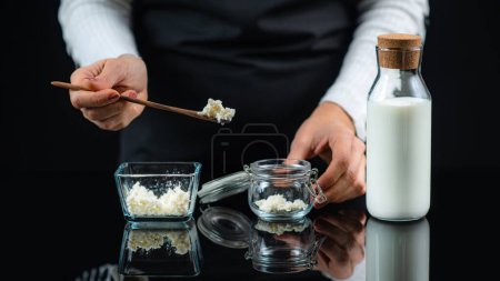 Photo for Kefir grains on a wooden spoon over a jar, Woman making kefir at home. - Royalty Free Image