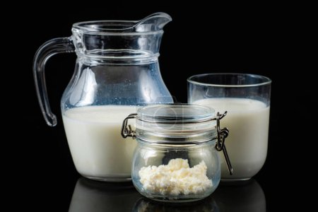 Téléchargez les photos : Boisson laitière fermentée probiotique au kéfir. Grains de kéfir dans un bocal et kéfir en bouteilles sur fond noir. - en image libre de droit