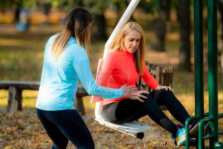 Téléchargez les photos : Women Friends Exercising in Public Park. Femme faisant de l'exercice pour les jambes sur la machine. Automne, Automne. - en image libre de droit