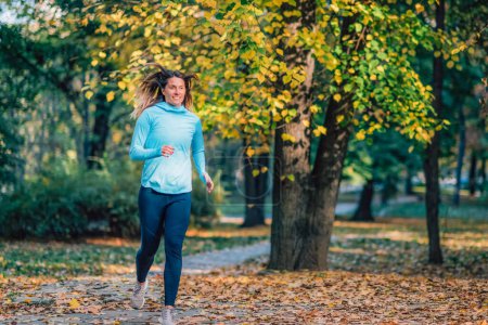Téléchargez les photos : Une femme court dans un parc public à l'automne. - en image libre de droit