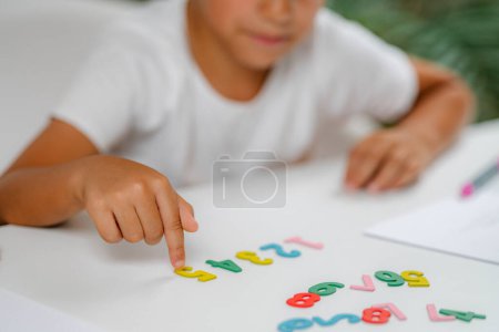 Photo for Preschooler boy sitting at the desk, playing with numbers - Royalty Free Image