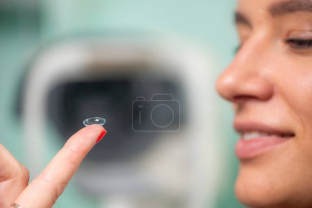 Téléchargez les photos : Ophtalmologiste compétent place doucement lentille de contact souple, assurant le confort du patient et une vision claire dans un environnement clinique professionnel - en image libre de droit