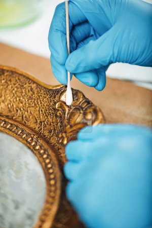Photo for Woman Cleaning and restoring an antique gold picture frame - Royalty Free Image