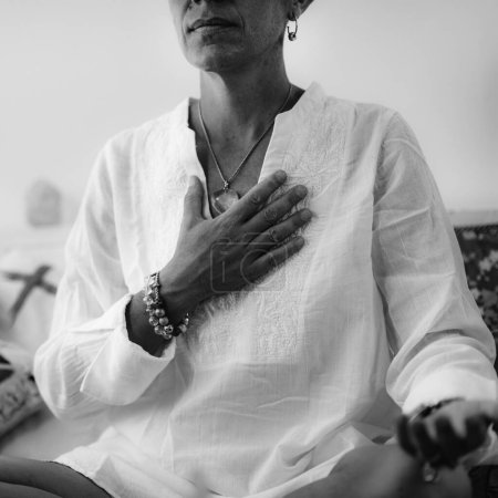 Foto de Meditación del Chakra del Corazón Auto-sanador. Mujer sentada en posición de loto con la mano derecha en el chakra del corazón. Despertar Espiritual
. - Imagen libre de derechos