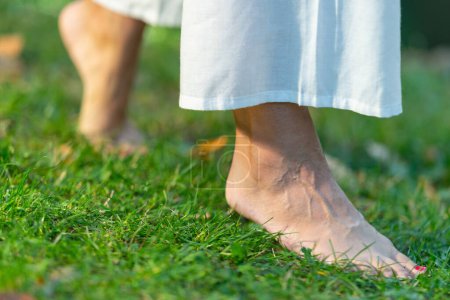 Téléchargez les photos : Voyage au sol comme une femme de yoga marche pieds nus, plaçant le projecteur sur ses pieds. Vivez la sérénité des étapes conscientes - en image libre de droit