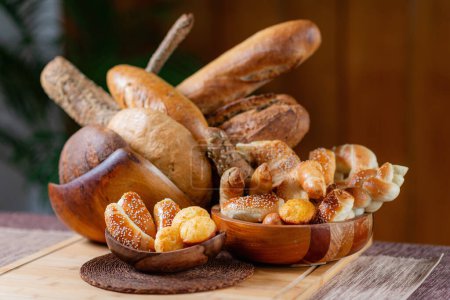 Foto de Delicias de panadería artesanal. Cuenco de madera rústico rebosante de productos horneados frescos en la mesa - Imagen libre de derechos