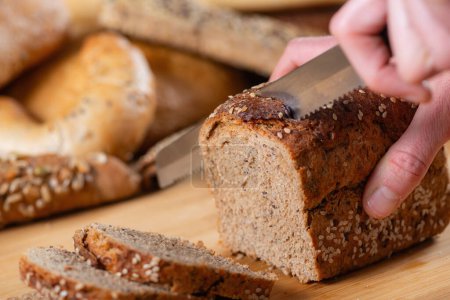 Photo for Close-up captures the art of slicing dark bread - Royalty Free Image