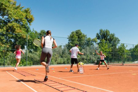 Foto de Grupo energético que participa en una sesión de entrenamiento de tenis cardiovascular de alta energía, combinando habilidades de fitness y tenis - Imagen libre de derechos