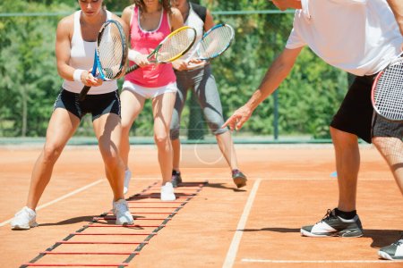 Téléchargez les photos : Groupe énergique participant à une séance d'entraînement de cardio-tennis à haute énergie, combinant fitness et tennis - en image libre de droit