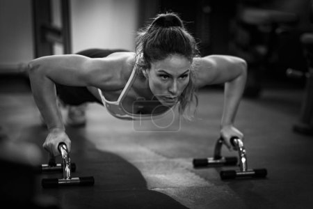 Foto de Mujer haciendo entrenamiento de fuerza push-up, mujer haciendo flexiones en el gimnasio. - Imagen libre de derechos