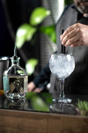 Bartender expertly stirs blending aromatic flavors Gin and Tonic cocktail