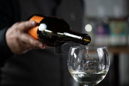 Barkeeper bereitet den Bicicletta Cocktail zu. Weißwein in ein Weinglas gießen.