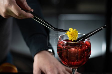 Téléchargez les photos : Barman ajoute une fleur délicate, mettant en valeur le cocktail Bicicletta avec un soupçon de charme botanique. - en image libre de droit