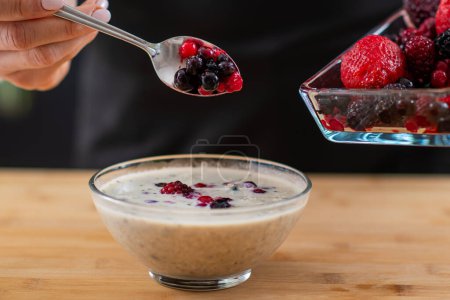 woman holding spoon full of berries and oatmeal, combining wholesome oats, creamy soy milk, and a medley of luscious berries for a vibrant and nutritious breakfast.  