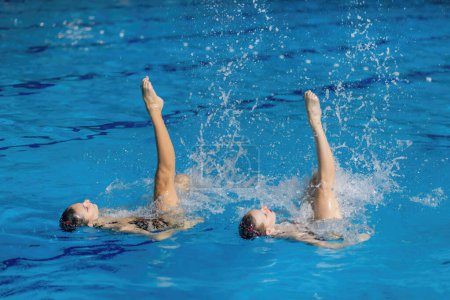 Synchronized swimming duo dances through the water, showcasing coordination and enchanting aquatic choreography