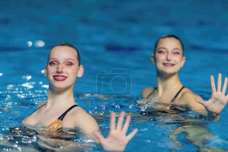 Téléchargez les photos : Performance d'un duo féminin de natation synchronisée, leurs mouvements fluides et leur élégance synchronisée créant une danse captivante dans la piscine - en image libre de droit
