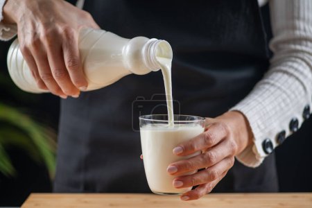 mujer vertiendo kéfir, una bebida láctea fermentada, rebosante de probióticos naturales Lacto y Bifido Bacterium.