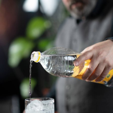 Téléchargez les photos : Les mains du barman versant tonique de haute qualité, préparation gin tonique cocktail. - en image libre de droit