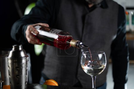 Barkeeper schenkt einen lebhaften roten Bitterlikör ein und stellt den ikonischen Bicicletta-Cocktail her.