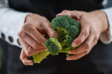 woman holding Fresh organic broccoli, a superfood rich in vitamin K, vitamin C, folic acid, potassium, phytonutrients, and fibers.