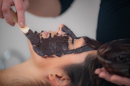 Foto de Esteticista Revitalizando la piel con la riqueza de una mascarilla facial de chocolate, un tratamiento de belleza decadente para un resplandor radiante y mimado - Imagen libre de derechos