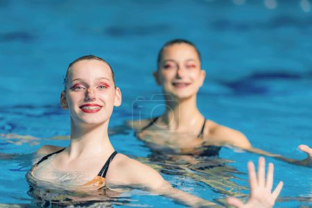 Performance of a female synchronized swimming duo, with fluid movements and synchronized elegance creating a captivating dance in the poo