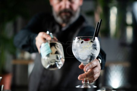 Téléchargez les photos : Cocktail gin tonic parfaitement préparé avec glaçons, herbes de romarin et baies de genièvre. - en image libre de droit