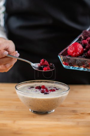 Superfood oatmeal, woman combining wholesome oats, creamy soy milk, and a medley of luscious berries for a vibrant and nutritious breakfast.