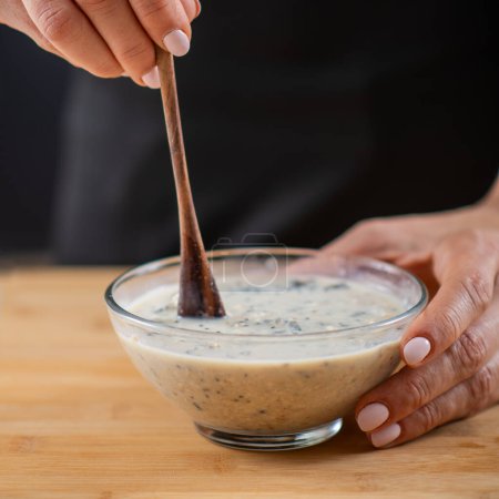Foto de Mujer preparando harina de avena con avena, leche de soja y proteína vegetal en polvo, mostrando la fusión de salud y sabor - Imagen libre de derechos