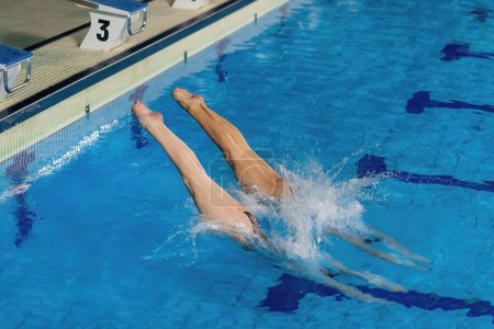 Téléchargez les photos : Grâce synchronisée, les femmes qui font le duo sautent dans la piscine - en image libre de droit