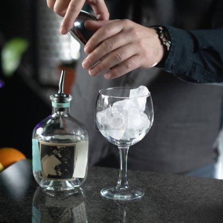 Gin Tonic Cocktail Preparation - Barkeeper füllt das Glas mit Eiswürfeln.