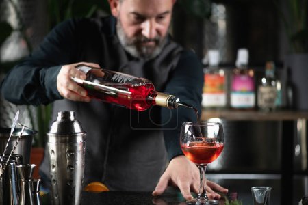 Bartender pours a vibrant red bitter liqueur, crafting the iconic Bicicletta cocktail.